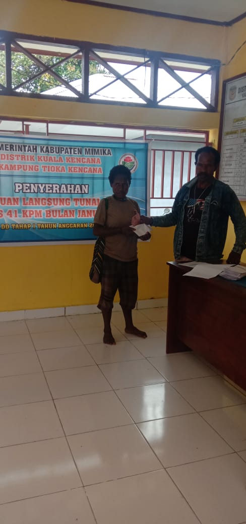 Bendahara Kampung Tioka Kencana Yotius Labene menyerahkan bantuan langsung tunai kepada warga