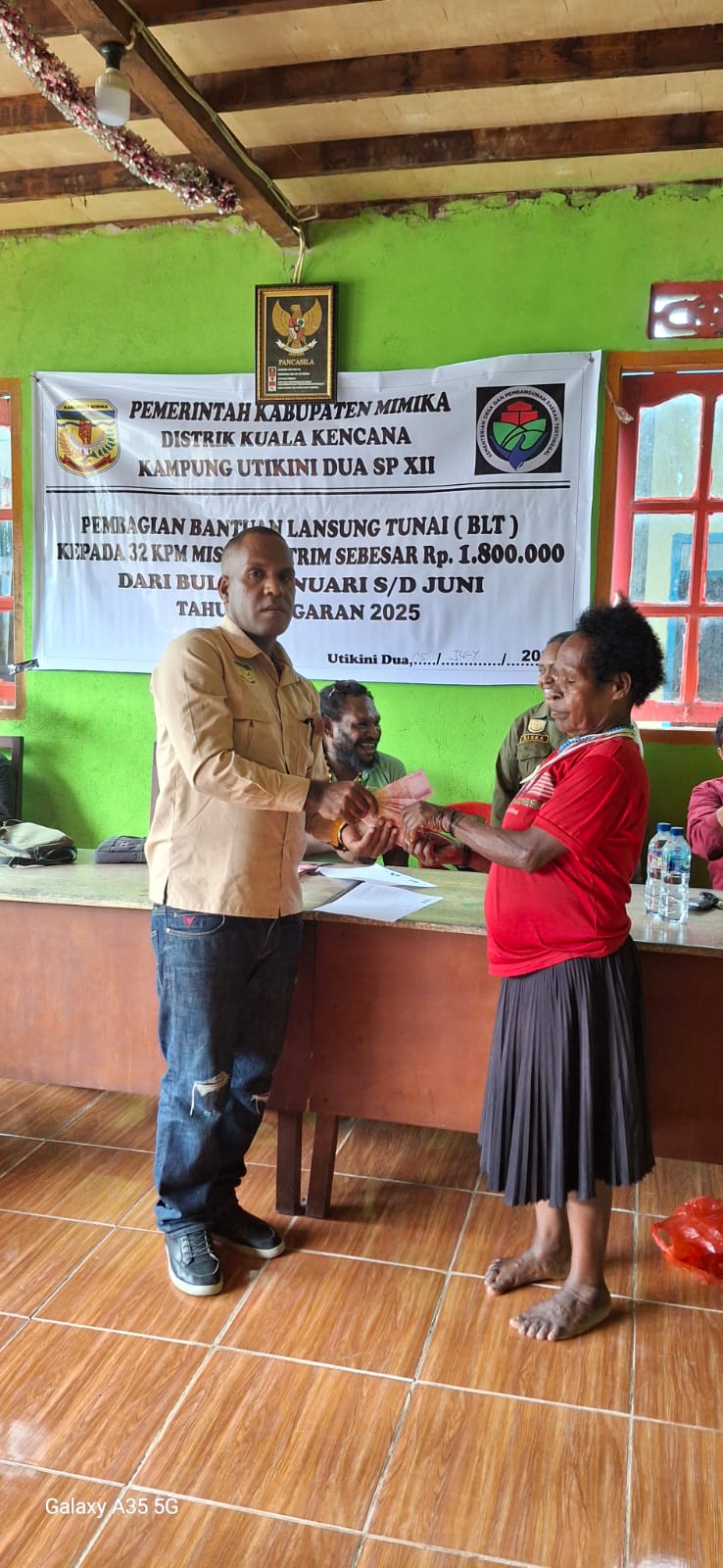 Kepala Kampung Utikini Dua saat menyerahkan Bantuan Langsung Tunai kepada warga