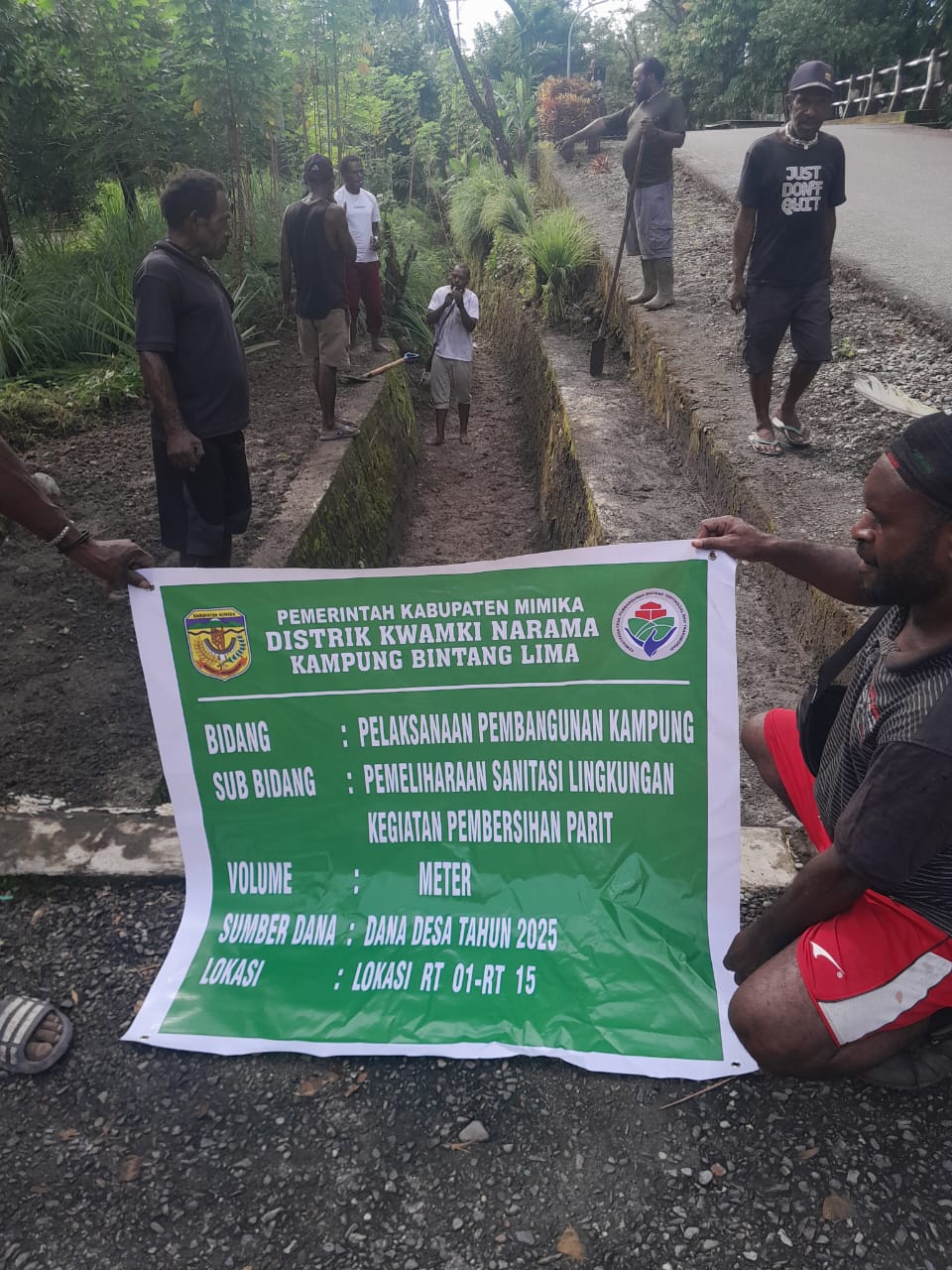 Warga mengabadikan momen sambil memegang spanduk dan Parit yang telah dibersihkan