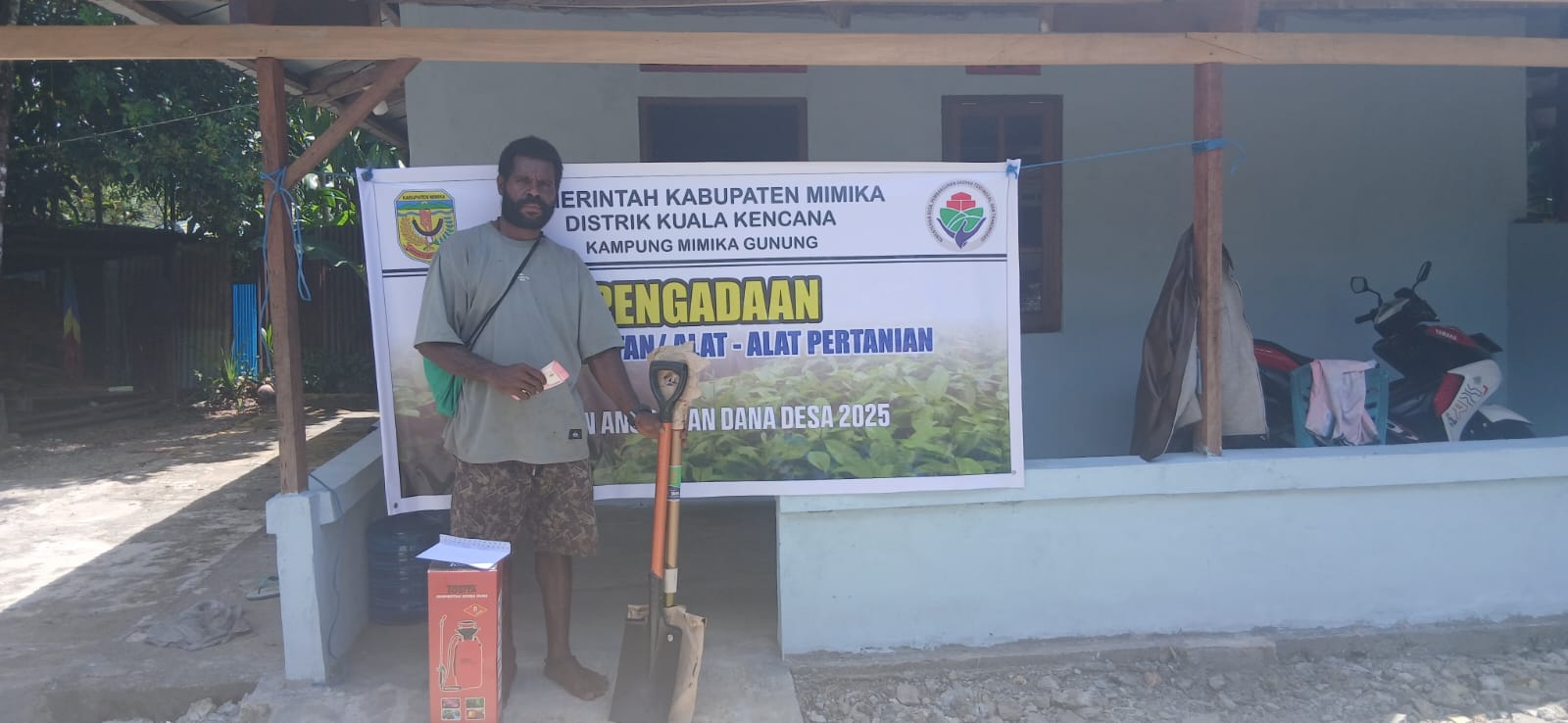 Seorang warga Kampung Mimika Gunung saat menerima bantuan peralatan pertanian dan bibit 
