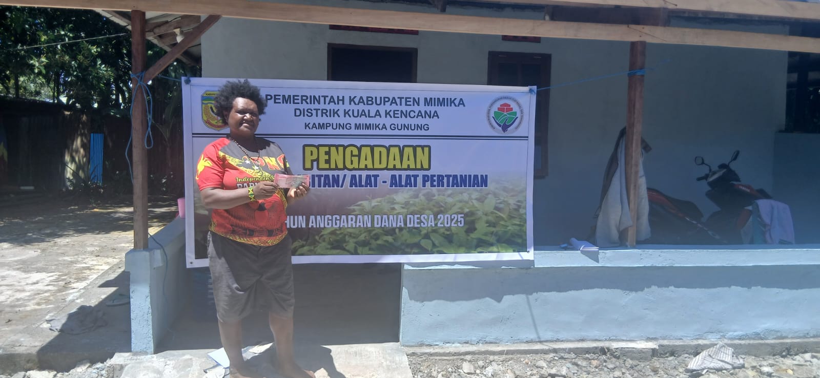Seorang warga Kampung Mimika Gunung saat menerima bantuan peralatan pertanian dan bibit 