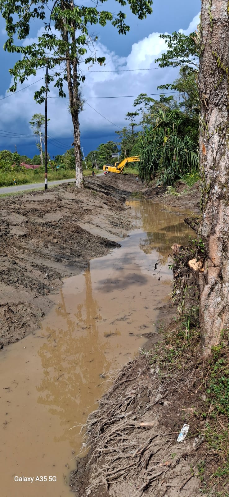 Excavator sedang mengangkat material dari dalam parit atau sungai