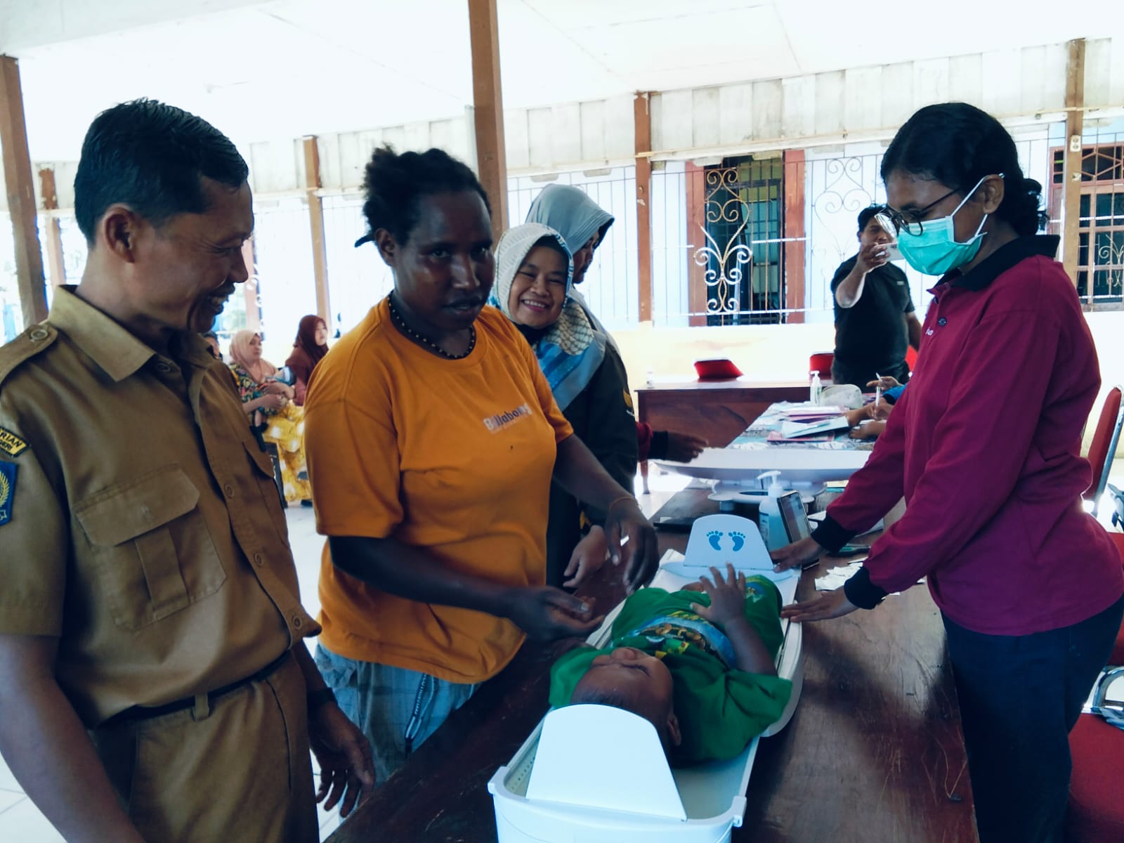 Seorang ibu membawa anaknya untuk pemeriksaan kesehatan di Posyandu disaksikan oleh Sekertaris Kampung Bhintuka Eko Kurniawan dan pendamping desa ibu Samsiah 
