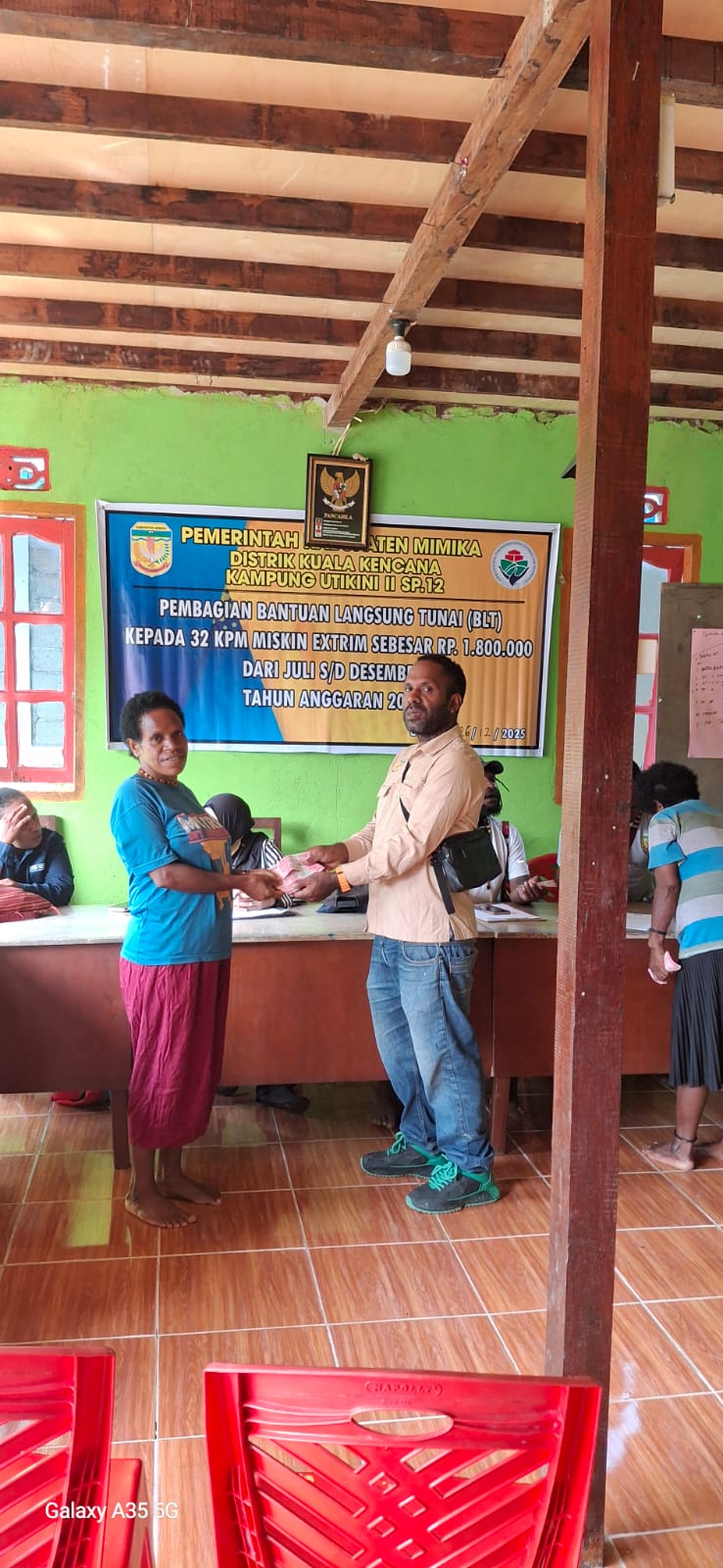 Kepala Kampung Utikini II, Merinus Kogoya didampingi pendamping desa saat menyerahkan BLT kepada seorang warga