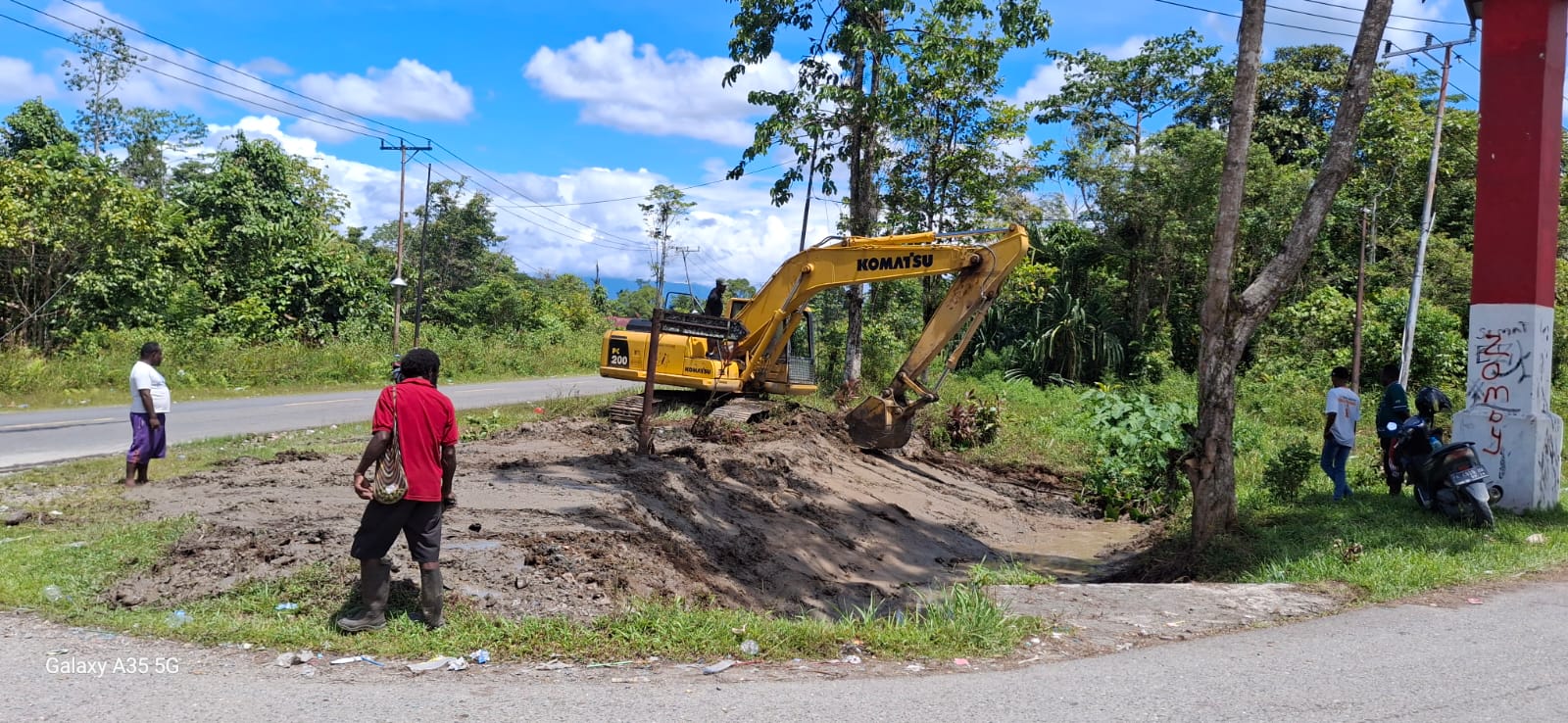 Excavator sedang mengangkat material dari dalam parit atau sungai