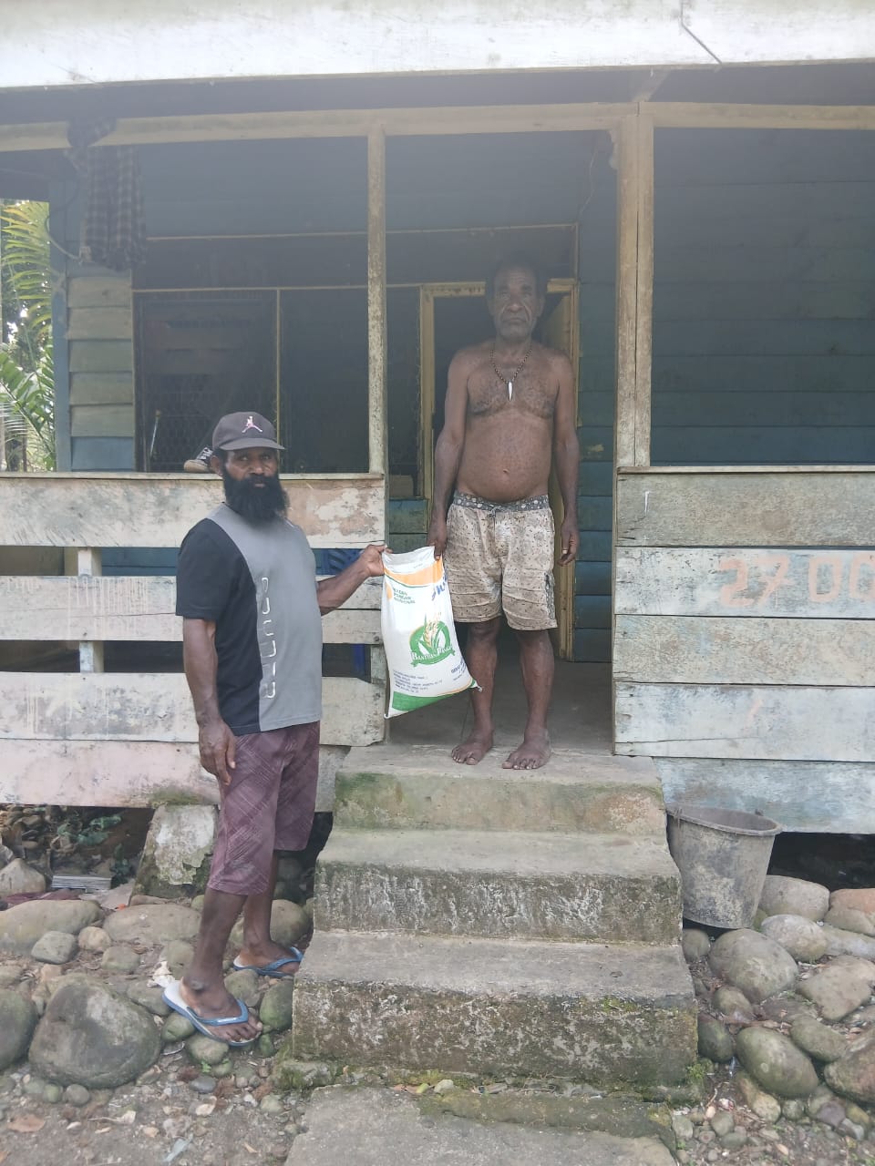 Aparatur Kampung Utikini I saat menyerahkan bantuan beras kepada warga