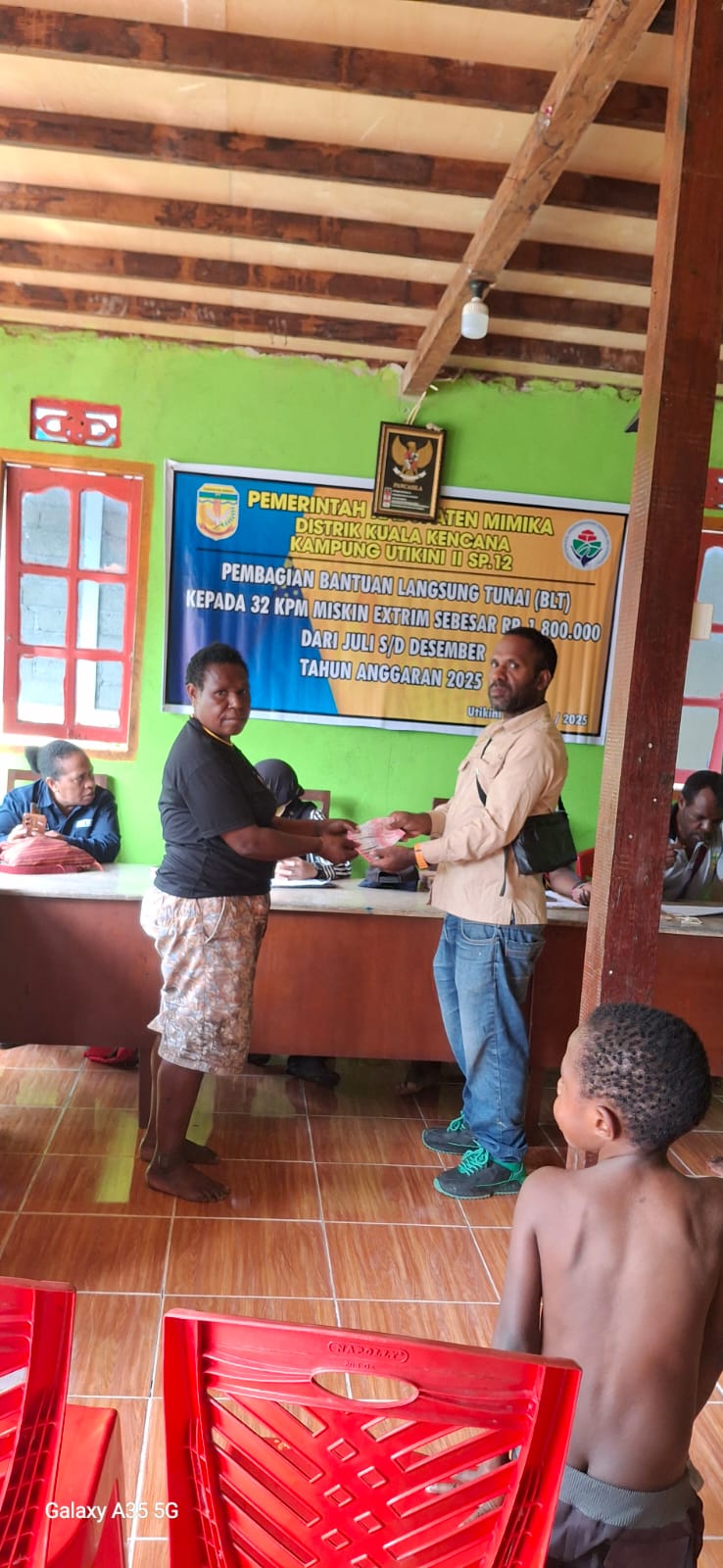 Kepala Kampung Utikini II, Merinus Kogoya didampingi pendamping desa saat menyerahkan BLT kepada seorang warga