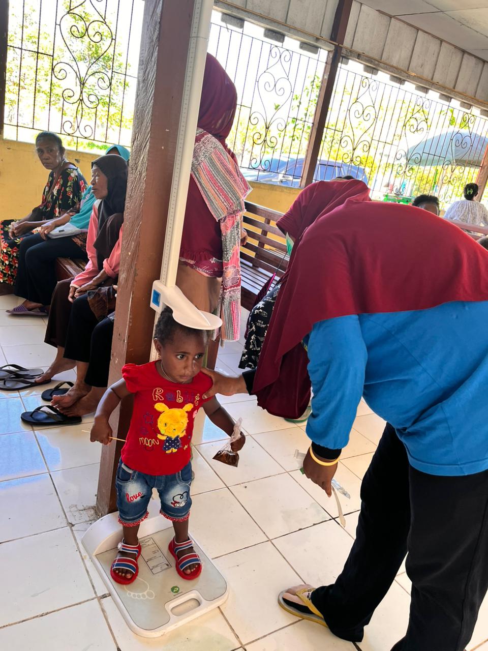 Seorang kader posyandu saat mengukur tinggi badan seorang balita 