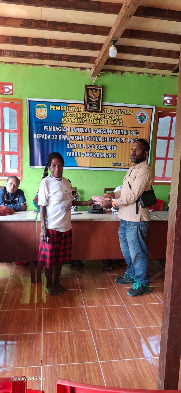 Kepala Kampung Utikini II, Merinus Kogoya didampingi pendamping desa saat menyerahkan BLT kepada seorang warga
