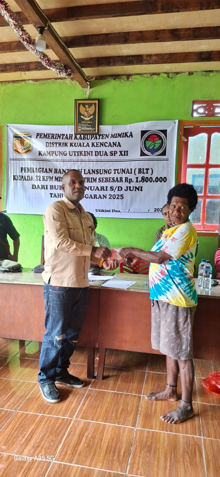Kepala Kampung Utikini Dua saat menyerahkan Bantuan Langsung Tunai kepada warga