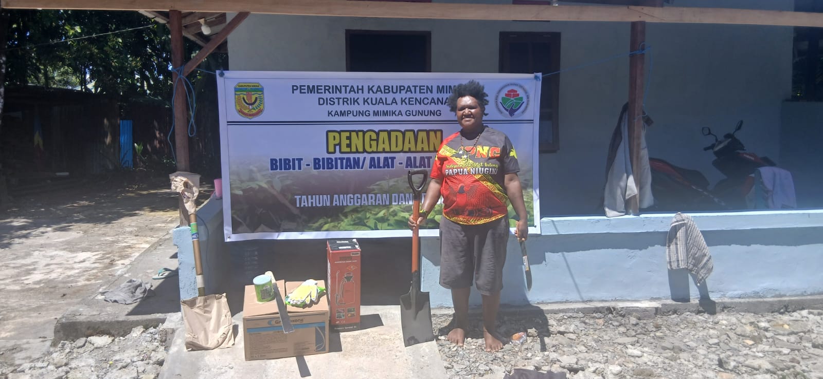 Seorang warga Kampung Mimika Gunung saat menerima bantuan peralatan pertanian dan bibit 
