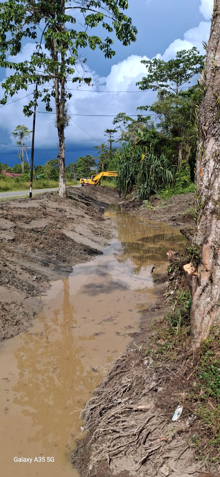 Excavator sedang mengangkat material dari dalam parit atau sungai