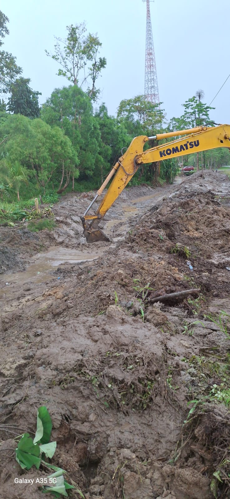 Excavator sedang mengangkat material dari dalam parit atau sungai
