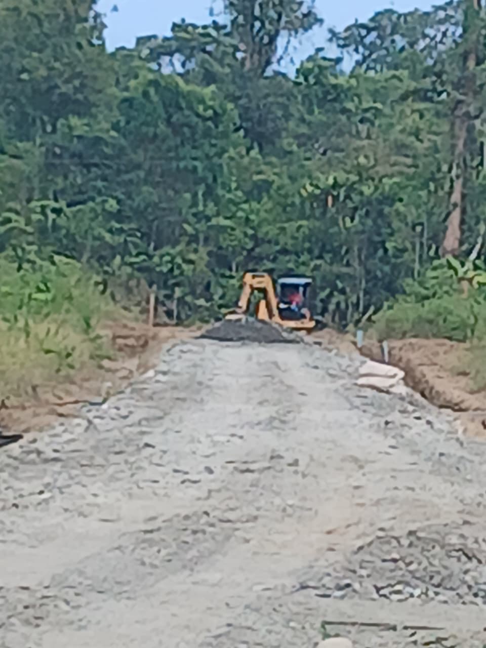 Alat berat berupa excavator saat merapikan material yang didumping oleh truk